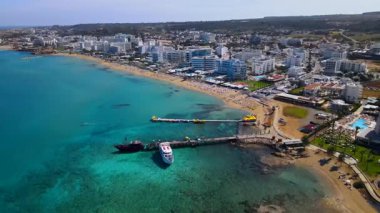 Protaras, Kıbrıs 'ta yaz günleri. Kamera turkuaz Akdeniz 'in ve otellerle çevrili sahil hattının üzerinden uçuyor..