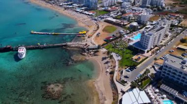 Protaras, Kıbrıs 'ta yaz günleri. Kamera turkuaz Akdeniz 'in ve otellerle çevrili sahil hattının üzerinden uçuyor..