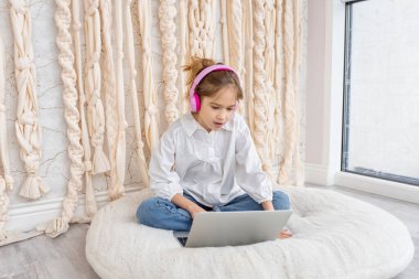 Caucasian school girl pupil in headphones studying online at home. Remote education concept. Teenage student distance learning on laptop, doing homework, watching, listening video lesson. Copy space