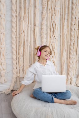 Happy caucasian girl in casual clothes, resting, listening to music in pink headphones. Good mood. Smiling peaceful carefree teeneger enjoying spending free time with favorite audio tracks. Hobby