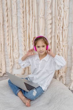 Caucasian teen girl school pupil in headphones studying online from home. Remote education concept. Teenage student distance learning on laptop, doing homework, watching, listening video lesson