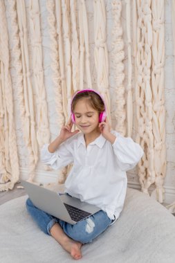 Happy caucasian girl in casual clothes, resting, listening to music in pink headphones. Good mood. Smiling peaceful carefree teeneger enjoying spending free time with favorite audio tracks. Hobby