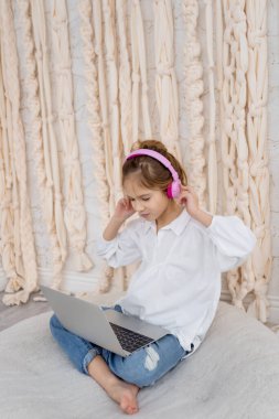 Teenage pupil using laptop notebook preparing for exams at home. Girl in headphone study online with video call, learn english language listen lecture. People, remote education, technology concept