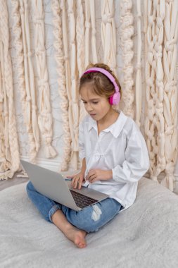 Teenage pupil using laptop notebook preparing for exams at home. Girl in headphone study online with video call, learn english language listen lecture. People, remote education, technology concept
