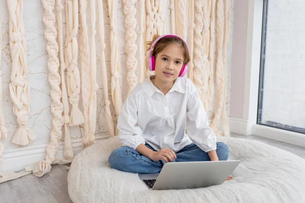 Caucasian teen girl school pupil in headphones studying online from home. Remote education concept. Teenager distance learning on laptop, doing homework, watching, listening video lesson. Copy space.