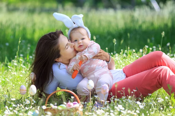 Happy family at Easter day having fun. Mother hug, kisses funny girl wearing rabbit ears with carrot. copy space. Happy childhood. Mom, daughter celebrate spring holliday. Concept of Easter Egg Hunt