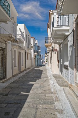 Chora, Andros Adası, Greec 'te beyaz boyalı evleri ve balkonları olan güneşli dar bir cadde.