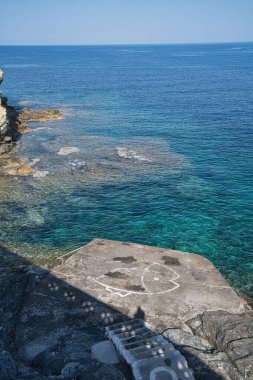 Andros Adası yakınlarındaki kayalık kıyı şeridi ve kristal berraklığında Ege Denizi suları.