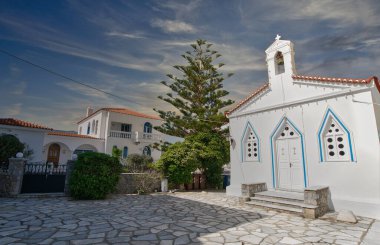 Andros Adası 'ndaki bulutlu gökyüzünün altında mavi detayları ve çan kulesiyle Beyaz Rum Ortodoks Kilisesi