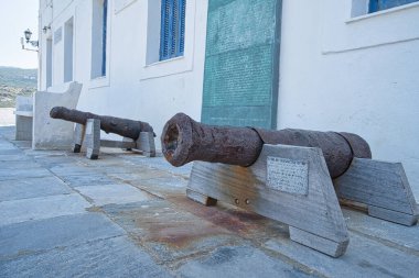 İki paslı tarihi top Chora, Andros, Greec 'teki beyaz bir binanın önünde duruyor.