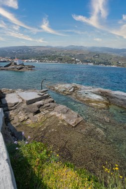 Andros Adası yakınlarındaki kayalık kıyı şeridi ve kristal berraklığında Ege Denizi suları.