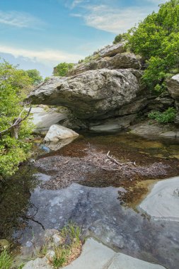 Andros Adası, Cyclades, Greec 'teki yemyeşil kayaların üzerinden akan manzaralı orman şelalesi.
