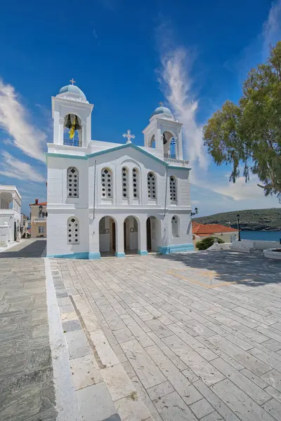 Mavi detayları ve Andros Adası 'ndaki çan kulesiyle dramatik bulutlu gökyüzü altında Beyaz Aziz George Ortodoks Kilisesi