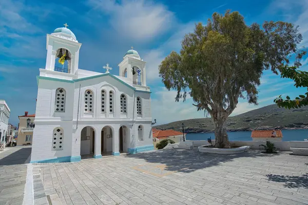 Mavi detayları ve Andros Adası 'ndaki çan kulesiyle dramatik bulutlu gökyüzü altında Beyaz Aziz George Ortodoks Kilisesi