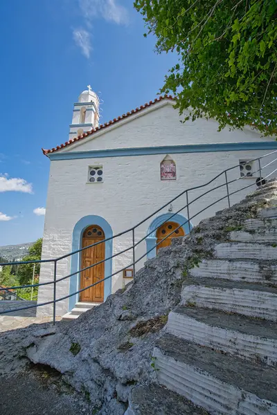 Andros Adası 'ndaki mavi detayları ve çan kulesiyle dramatik bulutlu gökyüzü altında Beyaz Rum Ortodoks Kilisesi