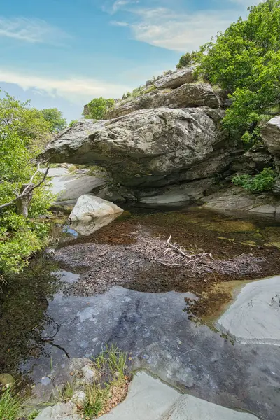 Andros Adası, Cyclades, Greec 'teki yemyeşil kayaların üzerinden akan manzaralı orman şelalesi.