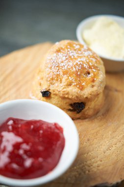 Çay, kahve, çilek reçeli ve pıhtılaşmış kremayla servis edilen güzel bir gurme çöreği. Geleneksel İngiliz yemekleri. Kakalar ve ikramlar