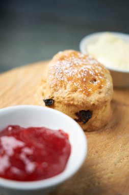 Çay, kahve, çilek reçeli ve pıhtılaşmış kremayla servis edilen güzel bir gurme çöreği. Geleneksel İngiliz yemekleri. Kakalar ve ikramlar