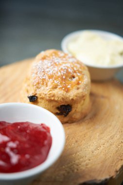 Çay, kahve, çilek reçeli ve pıhtılaşmış kremayla servis edilen güzel bir gurme çöreği. Geleneksel İngiliz yemekleri. Kakalar ve ikramlar