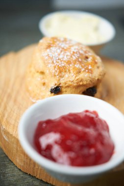 Çay, kahve, çilek reçeli ve pıhtılaşmış kremayla servis edilen güzel bir gurme çöreği. Geleneksel İngiliz yemekleri. Kakalar ve ikramlar