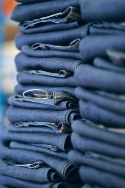 Kot fabrikasından yeni çıkmış bir kot pantolon yığını. Endüstriyel kumaş ve moda üretimi. Toptan satış için şık mavi kot kumaş..