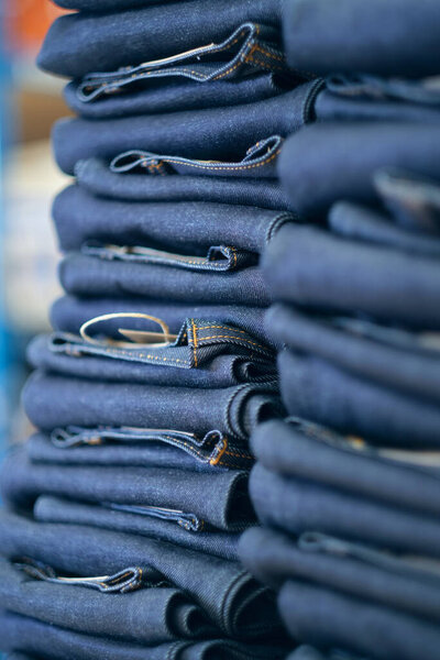 Куча джинсов из сырой джинсы, свежих с производственной линии на джинсовой фабрике. Промышленное производство тканей и одежды. Стильная джинсовая ткань для оптовой торговли.