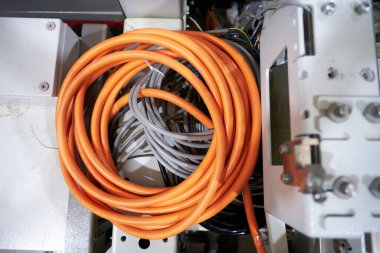 Fabrika ortamında turuncu ağır zırhlı endüstriyel elektrik kablosu. Elektrik makineleri için endüstriyel kablolar. Ağır iş imalatı.