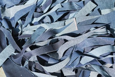Kot fabrikasında öğütülmüş çiğ kot kumaş yığını. Endüstriyel kumaş ve moda üretimi. Toptan satış ve kot geri dönüşümü için şık mavi kot kumaş.