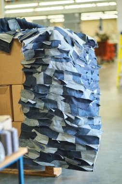 Kot fabrikasında öğütülmüş çiğ kot kumaş yığını. Endüstriyel kumaş ve moda üretimi. Toptan satış ve kot geri dönüşümü için şık mavi kot kumaş.