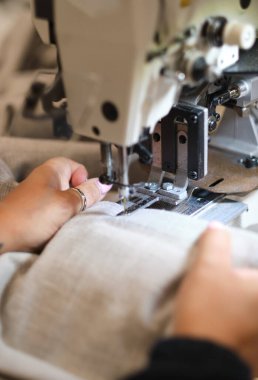 Eller tekstil fabrikasında çalışan bir dikiş makinesinde. Metal pamuk dikiş makinesi endüstrisi. Pamuk dikiş ve imalat tekstil endüstrisi. Metal askı rayları.