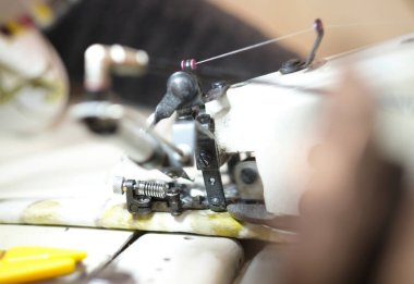 Eller tekstil fabrikasında çalışan bir dikiş makinesinde. Metal pamuk dikiş makinesi endüstrisi. Pamuk dikiş ve imalat tekstil endüstrisi. Metal askı rayları.