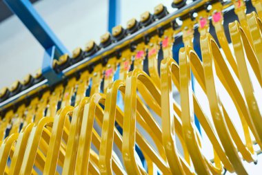 Tekstil fabrikasının sanayi bölgesinde metal bir paten. Metal silindirlerde metal yağ askıları. Pamuk dikiş ve imalat tekstil endüstrisi. Metal askı rayları.