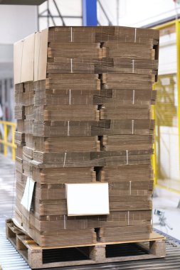 Bir paletin üzerinde yeni üretilmiş karton kutular taşınmak için paketleniyor. Bir karton kutu fabrikasında karton kutu depolama ve ulaşım çözeltisi.