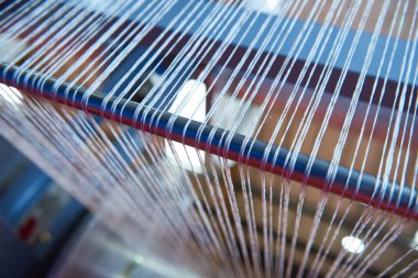 Bir dokuma fabrikasında pamuk iplikleri, moda ve tekstil endüstrisi için pamuk dokuma makinesi. Giysi ve moda için geleneksel tekstil kumaş üretimi iplik dokuması