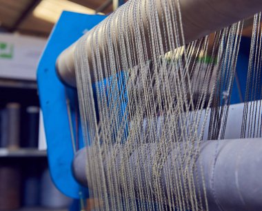 Bir dokuma fabrikasında pamuk iplikleri, moda ve tekstil endüstrisi için pamuk dokuma makinesi. Giysi ve moda için geleneksel tekstil kumaş üretimi iplik dokuması