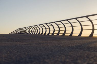 Sahildeki modern metal korkuluklar gezinti güvertesinde yürüyen insanları yüksekten düşmekten koruyor. Plaj denizi ve yaşam savunması. Akdeniz 'de yürümek, güneşin batışını izlemek.. 