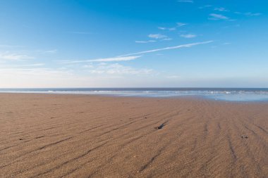 Kum dalgaları ve küçük bulut izleri olan güzel mavi gökyüzü ile güzel, güneşli bir kış günü..