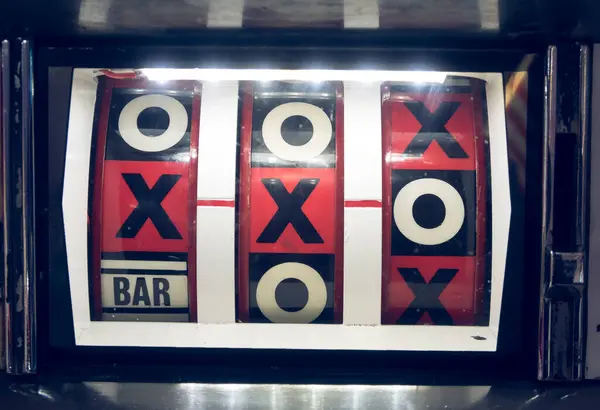 stock image A vintage antique coin slot gambling machine in an amusement arcade. One arm bandit retro analogue betting game machine. noughts and crosses. Cash money casino payout.