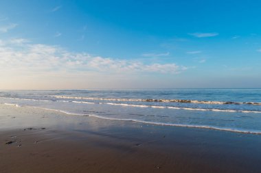 Gün batımında canlı mavi bir gökyüzü ve yansımasıyla plaja akan rahatlatıcı ve nazik dalgalar. Corona virüsünün kilitlenmesi sırasında temiz hava doğaya karışıyor.