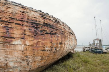 Çürüme ve bozulma belirtileri gösteren eski bir ahşap gemi enkazı. Paslı, çürümüş kalıntılarla kıyıda karaya vurmuş eski bir deniz gemisi. Doğa ve deniz eski teknelere zarar veriyor..