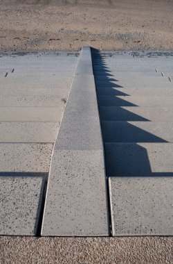 Güneşli bir kış günü sahile inen buz gibi soğuk adımlar. Deniz kıyısında. Deniz savunması ve merdivenler altın kumun üzerinde.