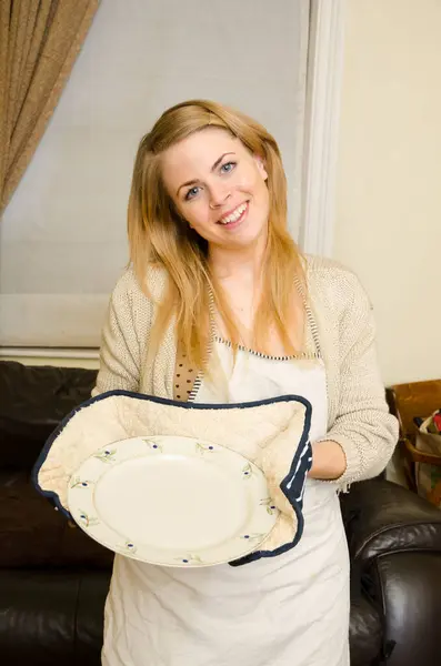 Stock image A beautiful vibrant youthful young girl with golden blonde hair, smiling with happiness and joy, with an empty baking plate,apron and oven gloves perfect for comping and compositing. 