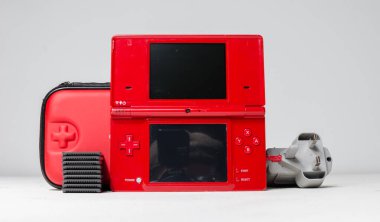 lodnon, england, 05/05/2019 A gloss red nintendo ds i hand held vintage console on a white studio background. Retro video gaming handset. nostalgic computer and arcade games.  clipart