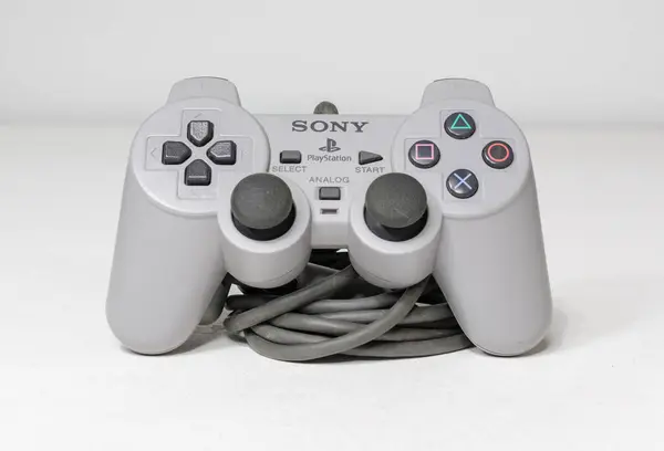 stock image london, uk 05/05/2020 A wired official play station 1 ps1 controller on a white studio backdrop. collectable rare home arcade video gaming. joystick and wireless remote technology.