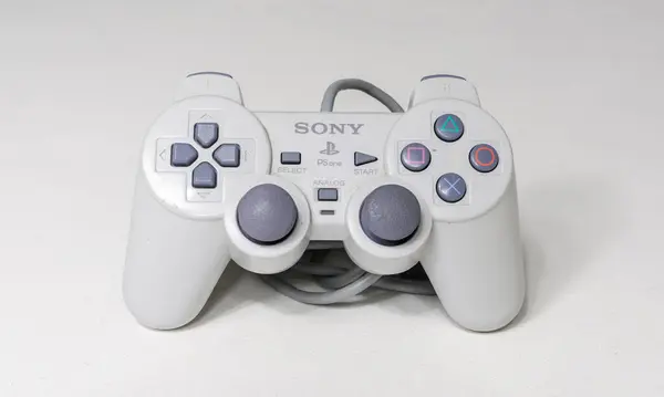 Stock image london, uk 05/05/2020 A wired official play station 1 ps1 controller on a white studio backdrop. collectable rare home arcade video gaming. joystick and wireless remote technology.