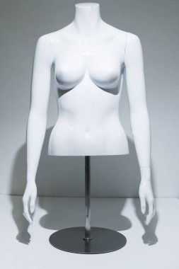 Ayarlanabilir kolları ve beyaz göğsü olan bir kadın manken gövdesi. Metal direkte ve zeminde büst görüntüsü. Perakende satış mağazaları için moda modeli. Perakende gösterimi.