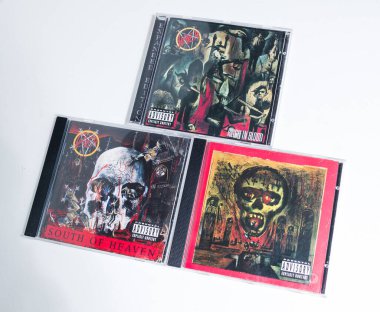 Kent, UK, 01.01.2023 Beyaz arka planda 3 avcı cd 'si. Cennetin güneyinde, kanla hüküm sürerken, uçurumda mevsimler geçirirken. Klasik temiz metal rock müzik CD 'leri. death metal sesleri.