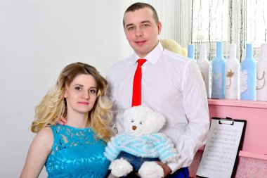 Çekici genç çift tatillerini evde kutluyor. Pembe bir piyanonun arka planında duruyor. Koca hamile karısına sarılıyor. Bir adam ve hamile karısı piyanonun başında duruyorlar. Ayakta ve