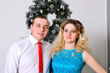 Çekici genç çift tatillerini evde kutluyor. Güzel bir Noel ağacının arkasında duran koca hamile karısına sarılıyor. Bir adam ve hamile karısı Noel ağacının yanında duruyor.