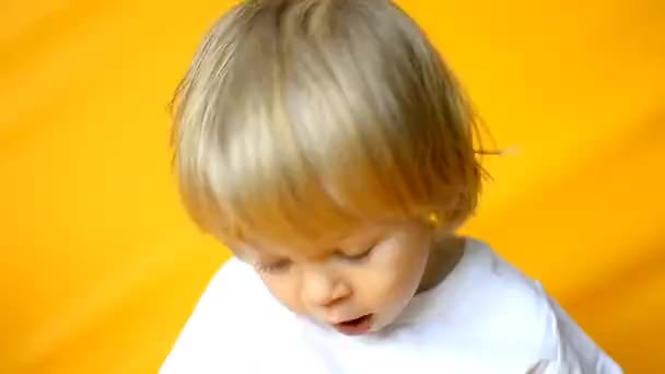 这孩子今年2岁 金发碧眼 穿着一件白色T恤 黄裤子 背景是黄色的 童年和家庭的概念 婴儿前视图黄色孤立的背景 — 图库视频影像